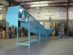 Inclined conveyor with magnetic head pulley to separate comingled ferrous and non-ferrous cans.